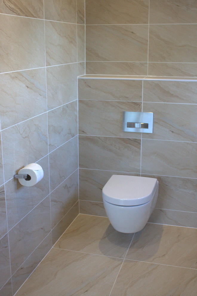 This is an example of a contemporary bathroom in Essex with a drop-in tub, an open shower and a wall-mount toilet.