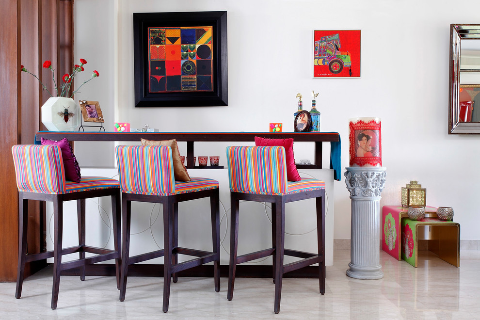 This is an example of a mid-sized eclectic seated home bar in Delhi with marble floors, brown benchtop, wood benchtops and grey floor.