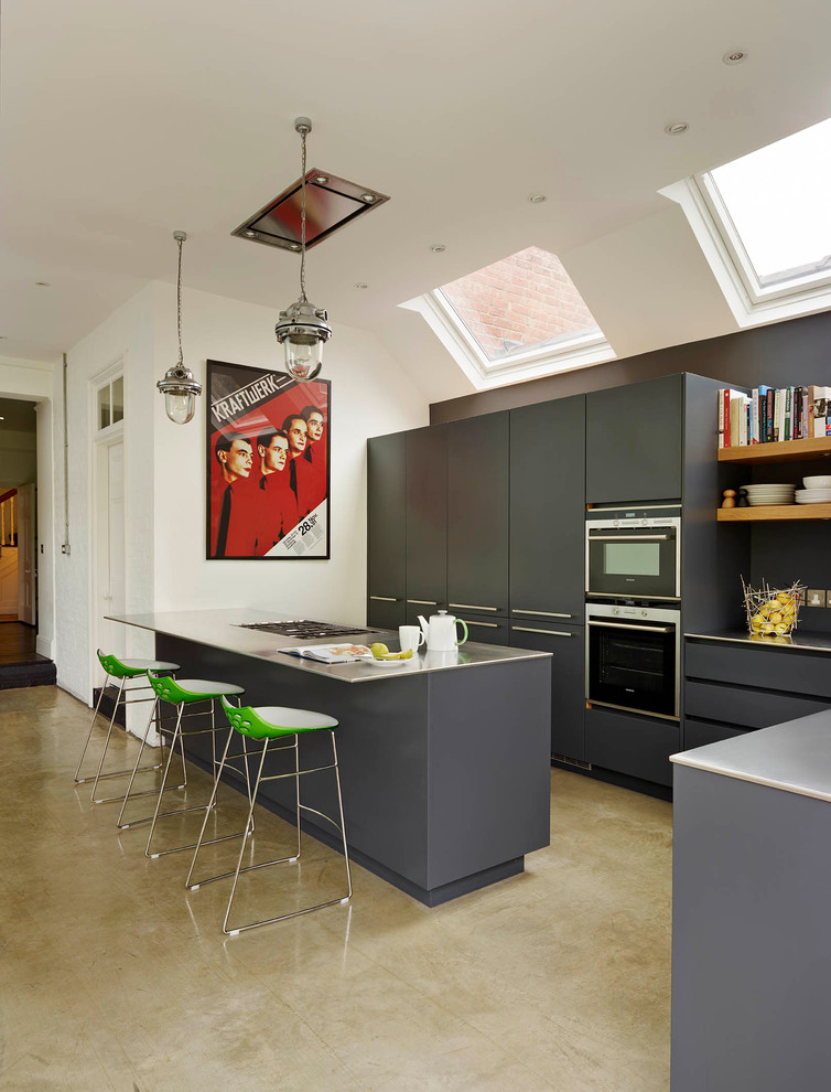 Design ideas for a large contemporary open plan kitchen in London with an undermount sink, flat-panel cabinets, grey cabinets, stainless steel benchtops, white splashback, ceramic splashback, stainless steel appliances and with island.
