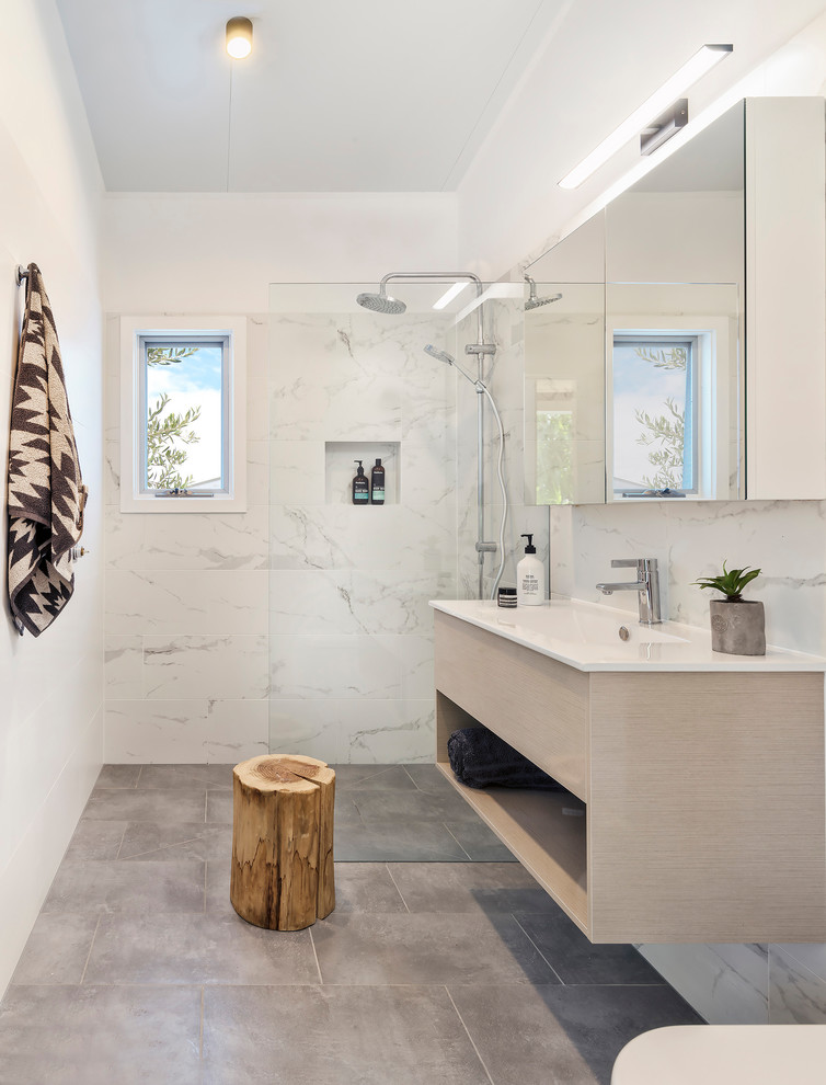 Photo of a beach style 3/4 bathroom in Melbourne with flat-panel cabinets, light wood cabinets, a corner shower, a one-piece toilet, white tile, marble, white walls, an integrated sink, grey floor, an open shower and white benchtops.