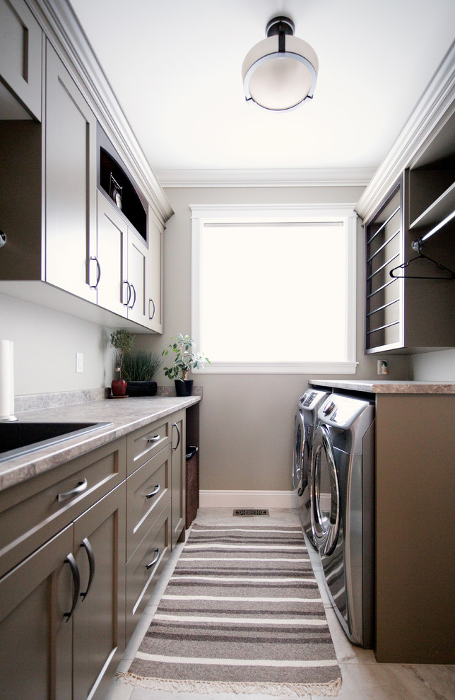 Design ideas for a mid-sized traditional galley dedicated laundry room in Vancouver with a drop-in sink, shaker cabinets, brown cabinets, laminate benchtops, grey walls, porcelain floors and a side-by-side washer and dryer.