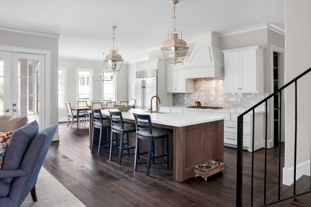 Photo of a large traditional galley open plan kitchen in Houston with a farmhouse sink, white cabinets, quartzite benchtops, grey splashback, marble splashback, stainless steel appliances, with island, brown floor, white benchtop, shaker cabinets and dark hardwood floors.