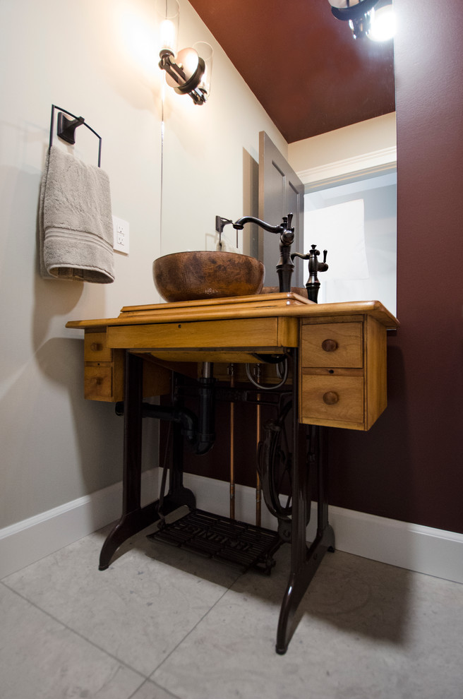 This is an example of a small transitional bathroom in Other with a vessel sink, furniture-like cabinets, light wood cabinets, wood benchtops, a two-piece toilet, beige tile, stone tile, red walls and limestone floors.