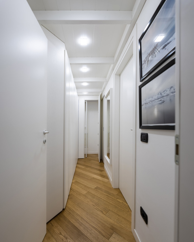 ミラノにある高級な小さな北欧スタイルのおしゃれな廊下 (白い壁、ラミネートの床、茶色い床、板張り天井) の写真