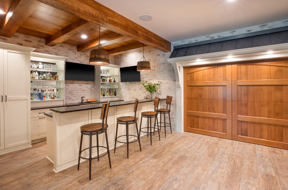 Basement - large country look-out vinyl floor, shiplap ceiling and brick wall basement idea in Columbus with a bar, a standard fireplace and a stone fireplace