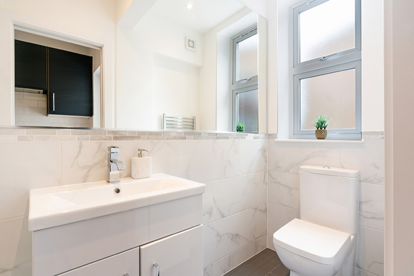 Photo of a small contemporary 3/4 bathroom in London with flat-panel cabinets, white cabinets, an open shower, white tile, ceramic floors, a drop-in sink, grey floor, a sliding shower screen, a niche, a single vanity and a freestanding vanity.