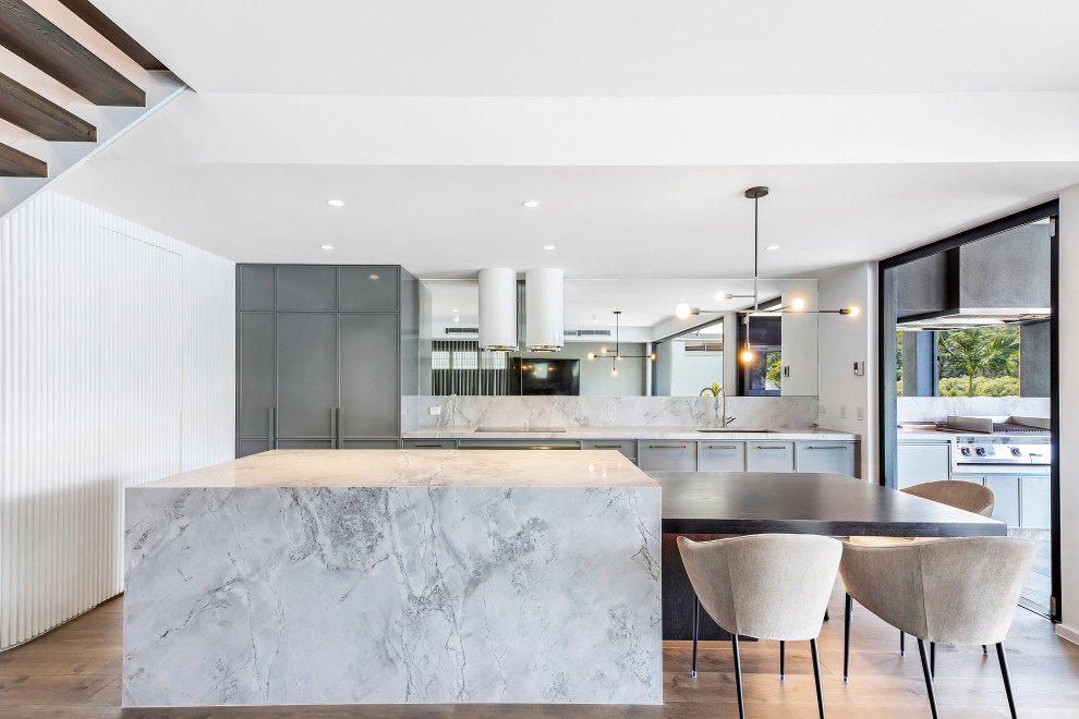 Contemporary kitchen in Gold Coast - Tweed with marble benchtops, white splashback, marble splashback, medium hardwood floors, with island and brown floor.