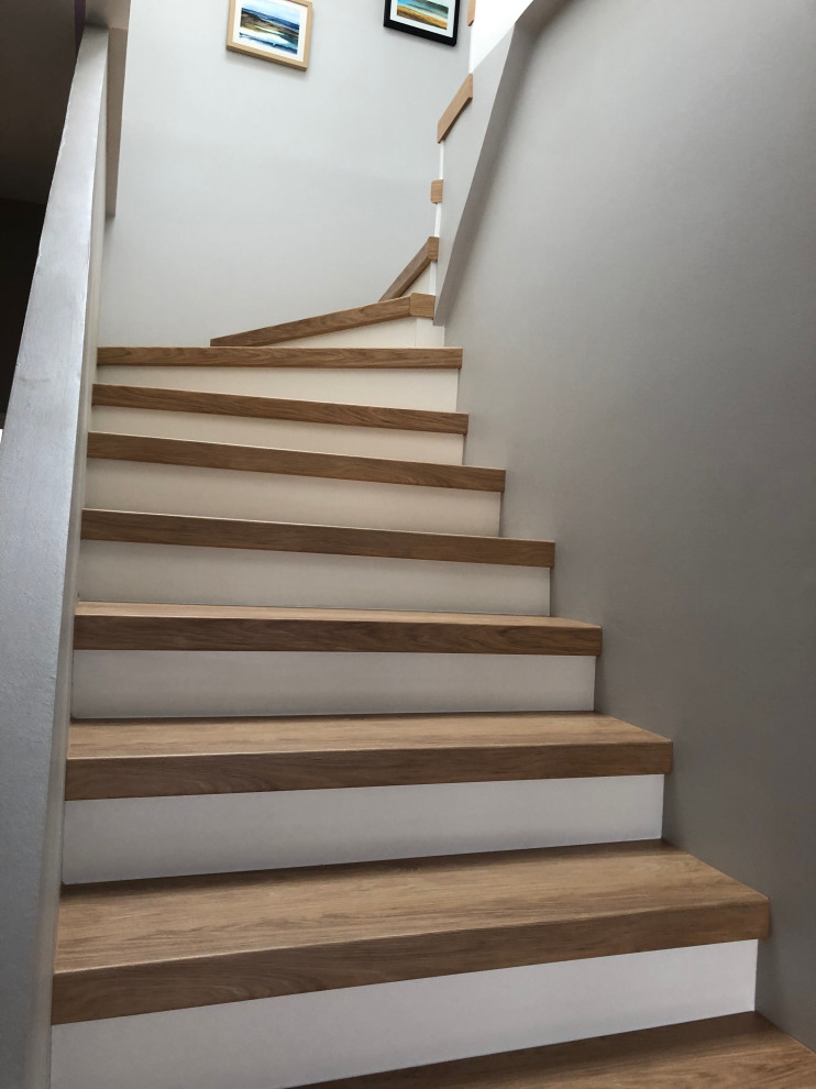 Imagen de escalera en U minimalista grande con escalones de madera, contrahuellas de madera, barandilla de varios materiales y papel pintado