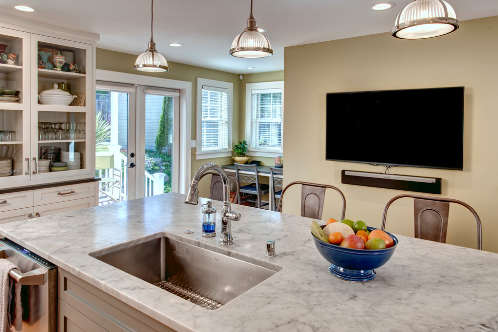 This is an example of a mid-sized traditional l-shaped kitchen in Seattle with an undermount sink, shaker cabinets, white cabinets, quartz benchtops, white splashback, ceramic splashback, stainless steel appliances, light hardwood floors and with island.