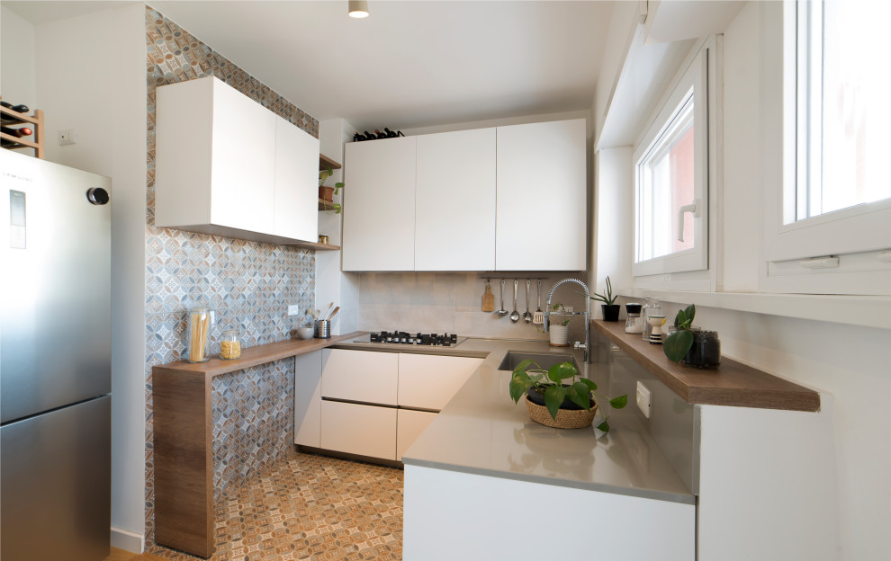 This is an example of a mid-sized modern u-shaped separate kitchen in Rome with an undermount sink, flat-panel cabinets, white cabinets, quartz benchtops, beige splashback, engineered quartz splashback, stainless steel appliances, porcelain floors, no island, multi-coloured floor and beige benchtop.