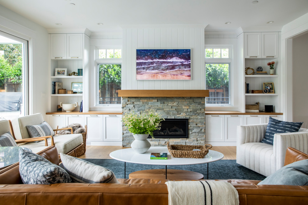 Design ideas for a large farmhouse open plan living room in San Francisco with medium hardwood flooring, brown floors, a wall mounted tv, white walls, a ribbon fireplace and a stacked stone fireplace surround.