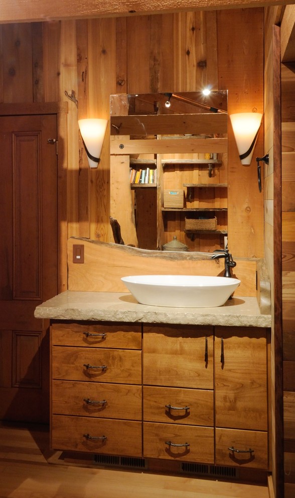 Photo of a mid-sized country bathroom in Sacramento with a vessel sink, flat-panel cabinets, medium wood cabinets, limestone benchtops and light hardwood floors.