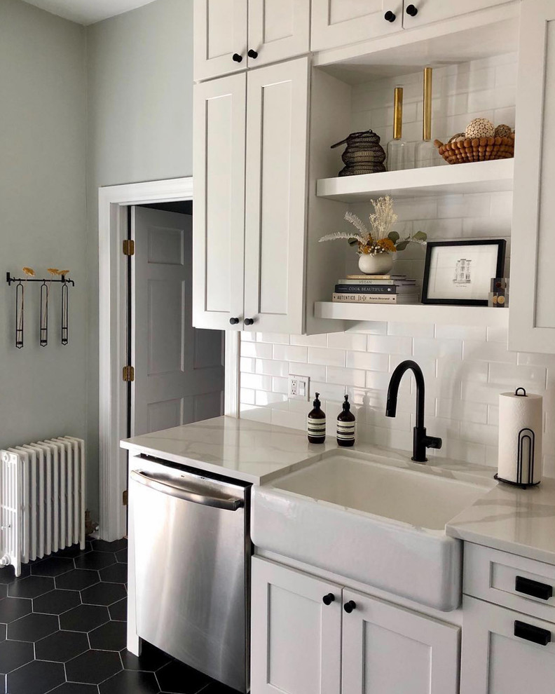 Inspiration for a mid-sized country u-shaped separate kitchen in Chicago with a farmhouse sink, shaker cabinets, white cabinets, quartz benchtops, white splashback, ceramic splashback, stainless steel appliances, porcelain floors, no island, black floor and white benchtop.