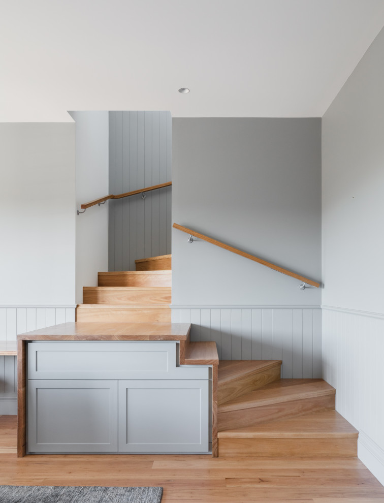 Photo of a transitional wood staircase in Sydney with wood risers and decorative wall panelling.