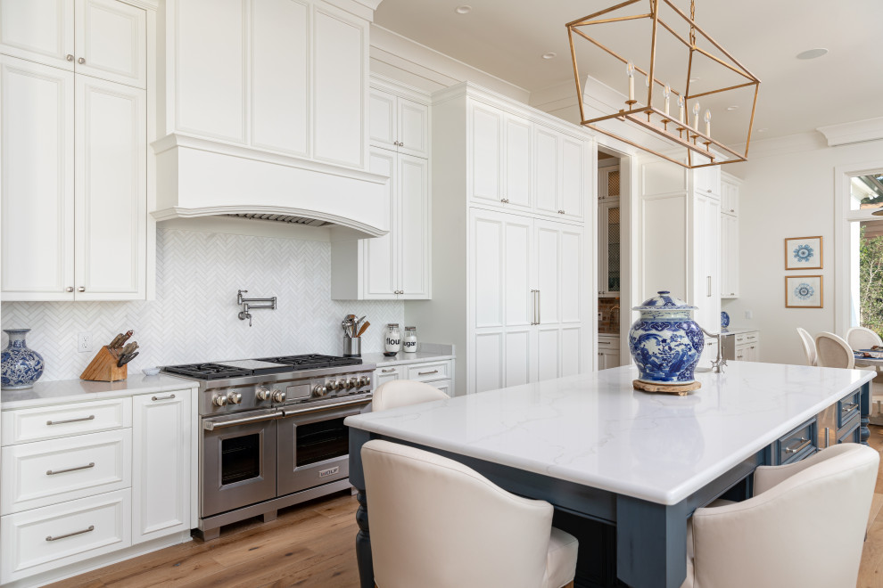 Inspiration for a large traditional u-shaped eat-in kitchen in Miami with white cabinets, white splashback, stainless steel appliances, with island, brown floor, white benchtop, recessed-panel cabinets, mosaic tile splashback and medium hardwood floors.
