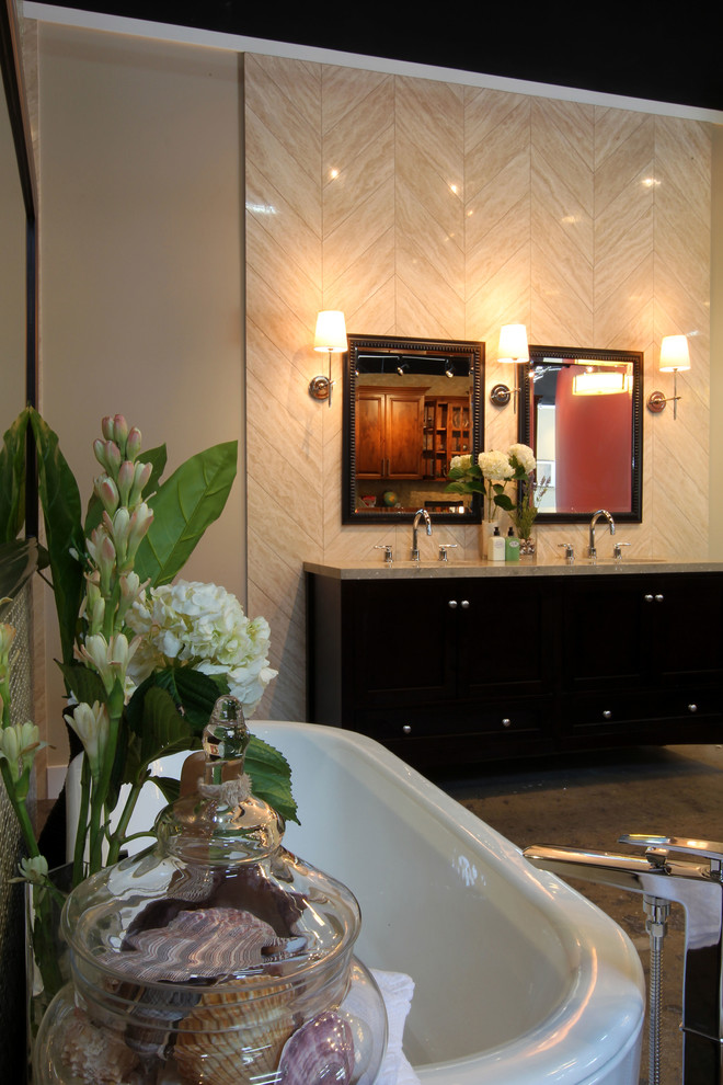 Inspiration for a large transitional master bathroom in Los Angeles with furniture-like cabinets, dark wood cabinets, a freestanding tub, an open shower, a wall-mount toilet, beige tile, glass sheet wall, beige walls, concrete floors, an undermount sink, limestone benchtops, grey floor and an open shower.