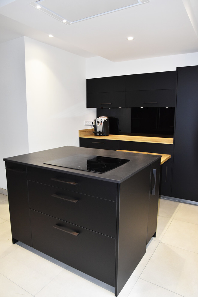 Photo of a mid-sized modern galley separate kitchen in Lyon with black appliances, ceramic floors, with island, beige floor, beaded inset cabinets, black cabinets, tile benchtops, black splashback, glass sheet splashback and a double-bowl sink.