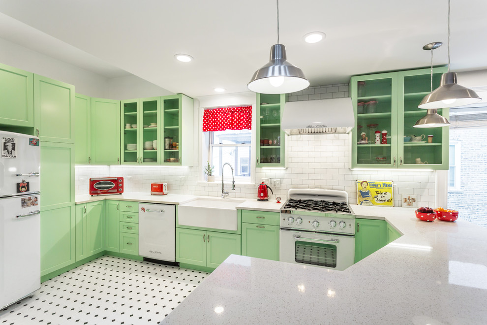 Inspiration for a mid-sized traditional kitchen in Chicago with a farmhouse sink, green cabinets, quartz benchtops, white splashback, subway tile splashback, white appliances, a peninsula, glass-front cabinets and multi-coloured floor.