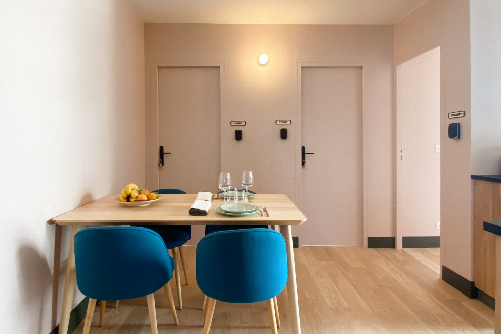 This is an example of a mid-sized contemporary open plan dining in Paris with pink walls, light hardwood floors and brown floor.