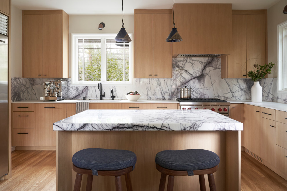 This is an example of a modern eat-in kitchen in San Francisco with light wood cabinets, marble benchtops, multi-coloured splashback, marble splashback, stainless steel appliances, with island and multi-coloured benchtop.