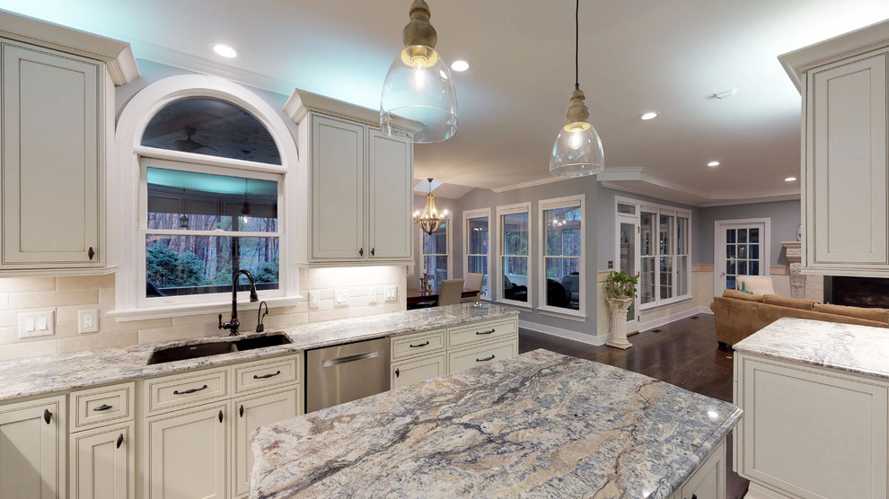 Inspiration for a large mediterranean l-shaped eat-in kitchen in Raleigh with an undermount sink, recessed-panel cabinets, beige cabinets, granite benchtops, beige splashback, stone tile splashback, stainless steel appliances, dark hardwood floors, with island, brown floor and blue benchtop.