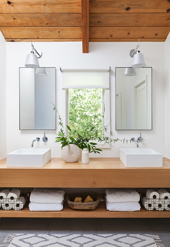Photo of a beach style bathroom in San Francisco with medium wood cabinets, white walls, a vessel sink and grey floor.