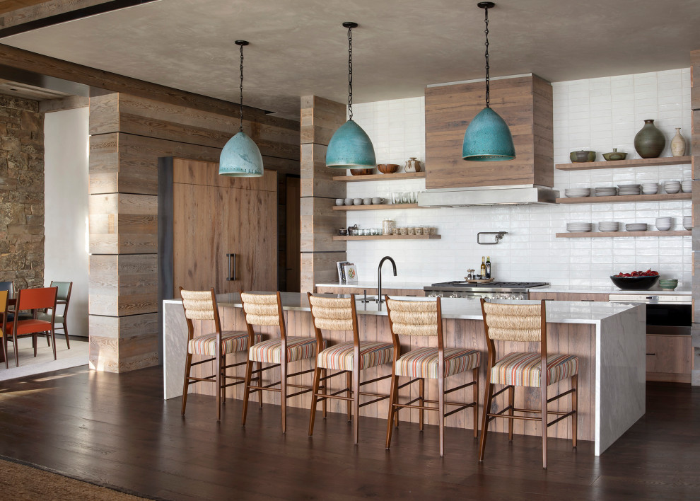 Kitchen - large rustic dark wood floor kitchen idea with an undermount sink, flat-panel cabinets, medium tone wood cabinets, marble countertops, white backsplash, ceramic backsplash, paneled appliances, an island and white countertops