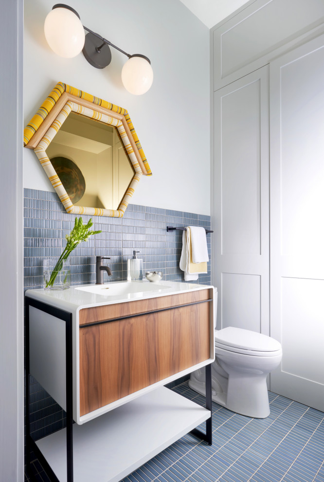Design ideas for a small transitional powder room in Dallas with furniture-like cabinets, medium wood cabinets, a one-piece toilet, blue tile, ceramic tile, blue walls, ceramic floors, an integrated sink, engineered quartz benchtops and white benchtops.