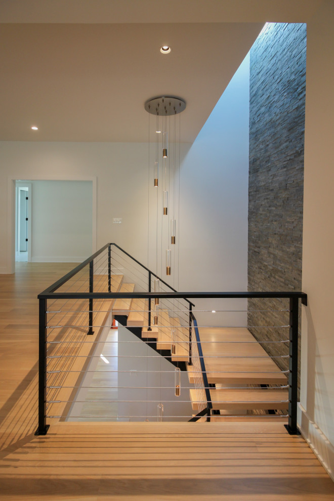 На фото: большая лестница на больцах в стиле фьюжн с деревянными ступенями, металлическими перилами и кирпичными стенами с
