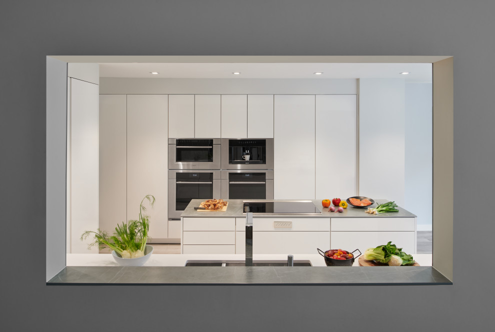 Idéer för ett mellanstort modernt grå kök, med en undermonterad diskho, släta luckor, vita skåp, bänkskiva i kvartsit, grått stänkskydd, rostfria vitvaror, vinylgolv, en köksö och grått golv
