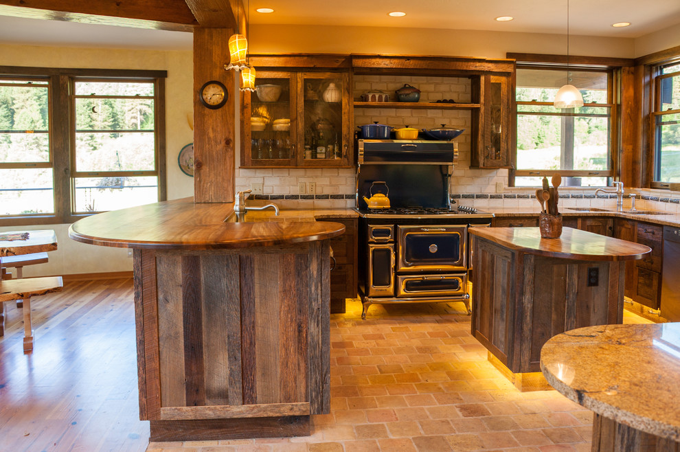 Example of a large mountain style u-shaped cement tile floor and beige floor open concept kitchen design in Seattle with recessed-panel cabinets, granite countertops, beige backsplash, ceramic backsplash, stainless steel appliances, an island, an undermount sink and dark wood cabinets