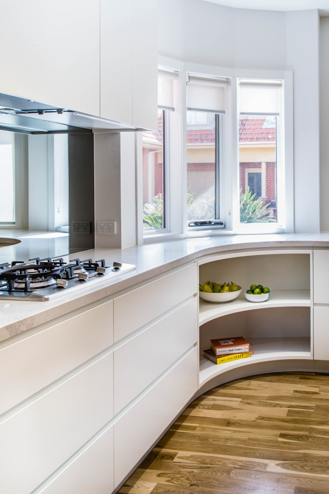 Photo of a mid-sized transitional l-shaped open plan kitchen in Melbourne with an undermount sink, flat-panel cabinets, white cabinets, quartz benchtops, grey splashback, mirror splashback, stainless steel appliances, medium hardwood floors, with island, yellow floor and multi-coloured benchtop.