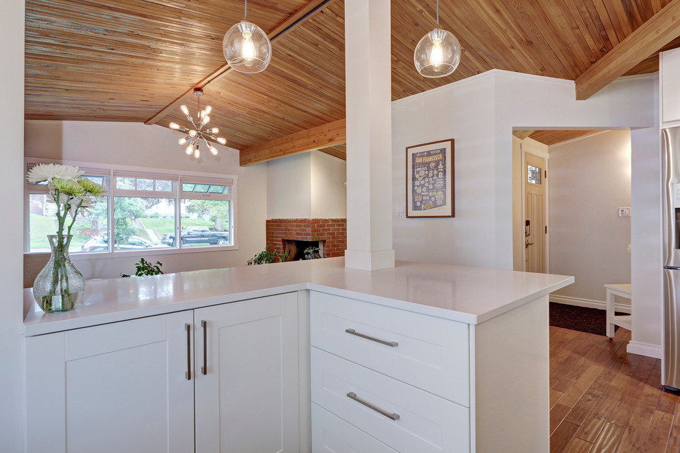Inspiration for a transitional u-shaped medium tone wood floor eat-in kitchen remodel in Calgary with an undermount sink, shaker cabinets, white cabinets, quartzite countertops, white backsplash, subway tile backsplash, stainless steel appliances and an island