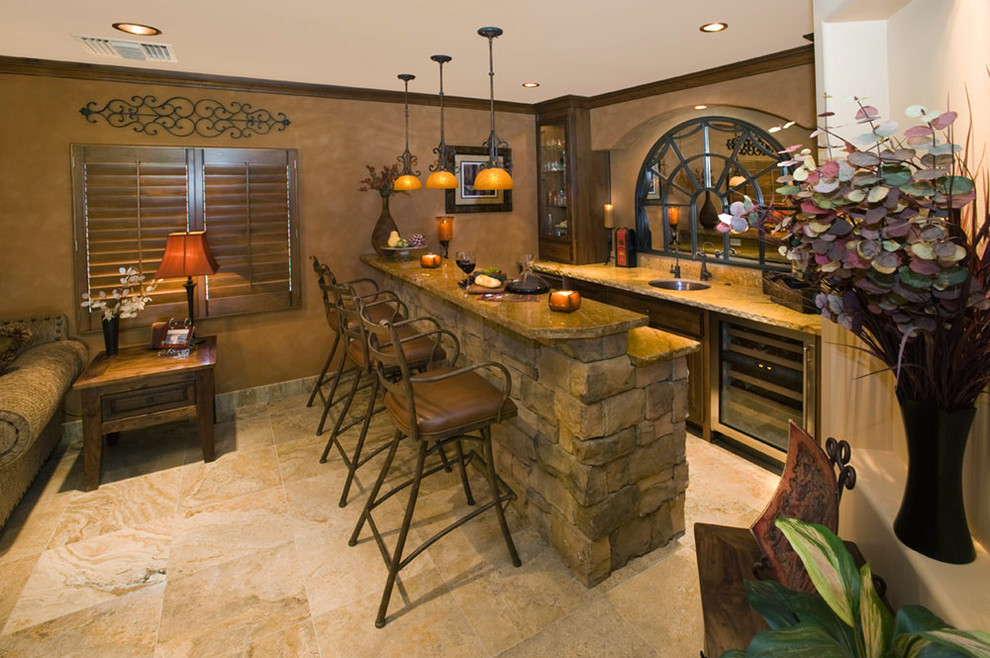 Large mountain style galley slate floor and beige floor seated home bar photo in Phoenix with an undermount sink, recessed-panel cabinets, dark wood cabinets, soapstone countertops, beige backsplash, stone slab backsplash and beige countertops