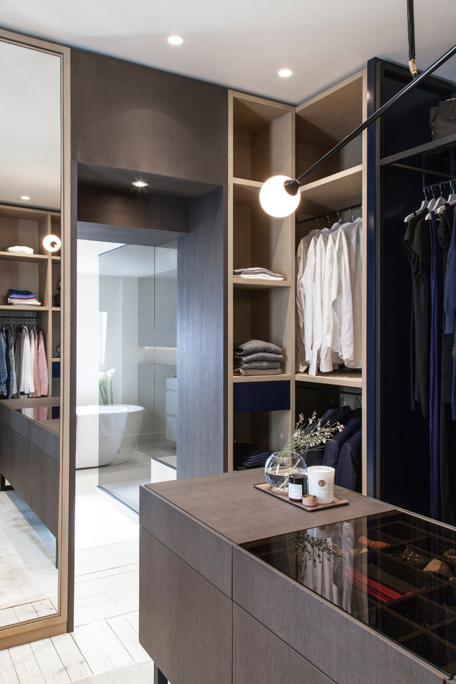 This is an example of a mid-sized contemporary men's dressing room in Paris with open cabinets, dark wood cabinets, light hardwood floors and white floor.