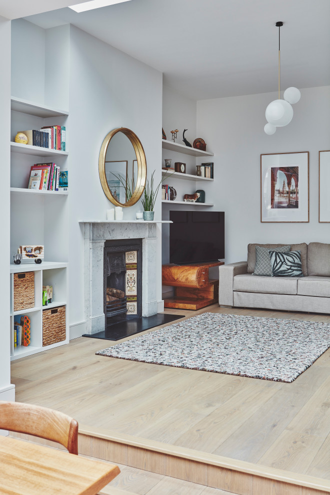 This is an example of a mid-sized modern open concept living room in London with grey walls, light hardwood floors, a standard fireplace, a stone fireplace surround and a corner tv.