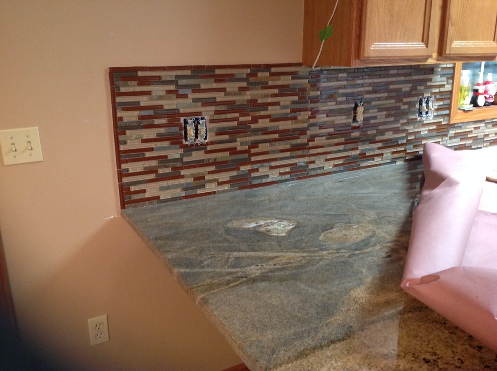 Inspiration for a l-shaped eat-in kitchen remodel with an undermount sink, flat-panel cabinets, brown backsplash, glass tile backsplash, stainless steel appliances and a peninsula