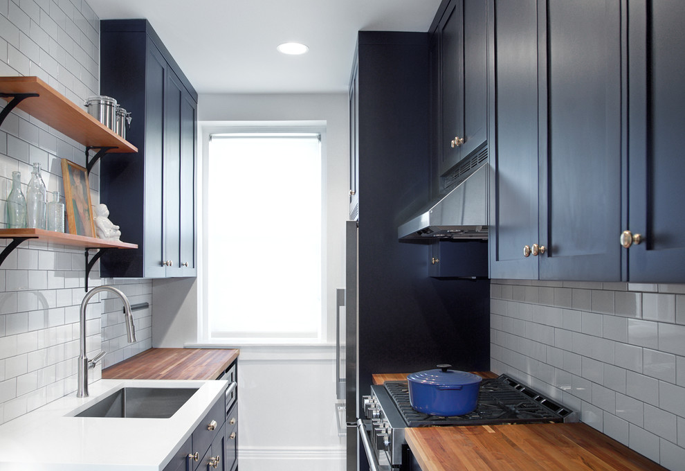 This is an example of a small traditional galley separate kitchen in New York with an undermount sink, shaker cabinets, blue cabinets, wood benchtops, white splashback, stainless steel appliances, marble floors, no island and subway tile splashback.