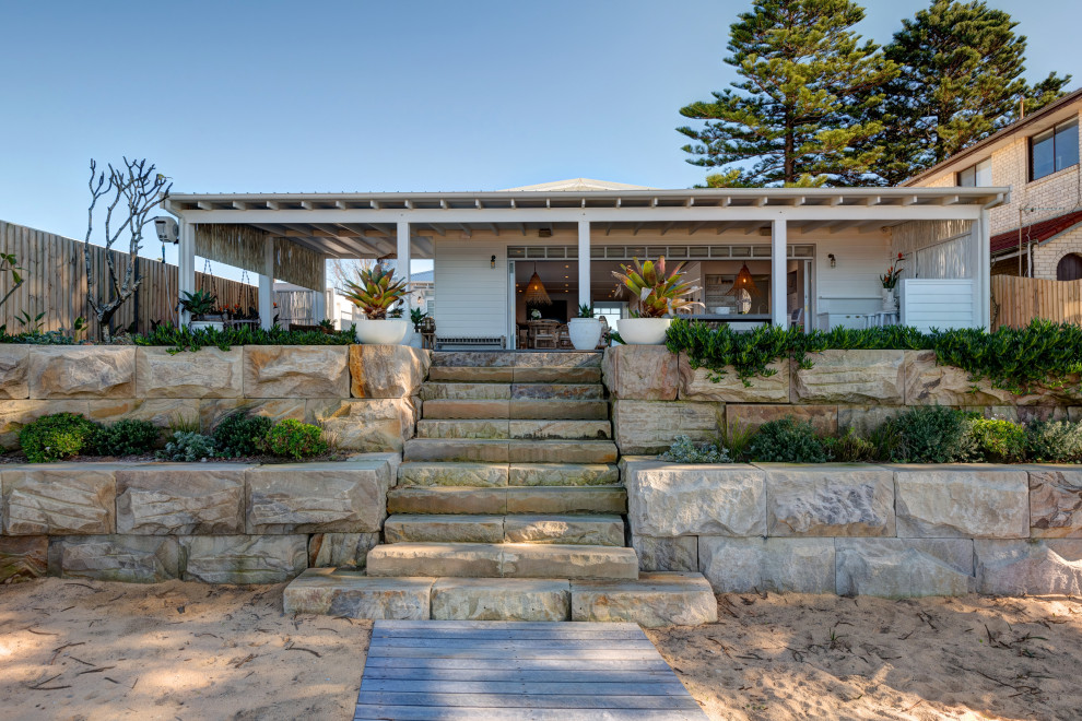 Inspiration for a large beach style two-storey white house exterior in Central Coast with wood siding, a metal roof and a white roof.