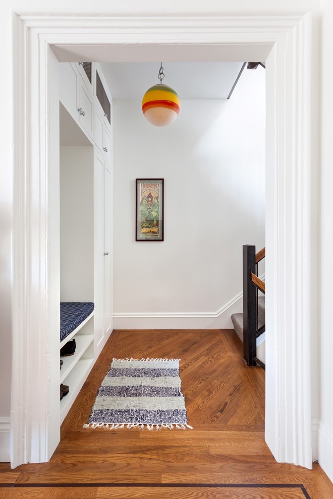 Mid-sized transitional hallway in New York with white walls, medium hardwood floors and brown floor.