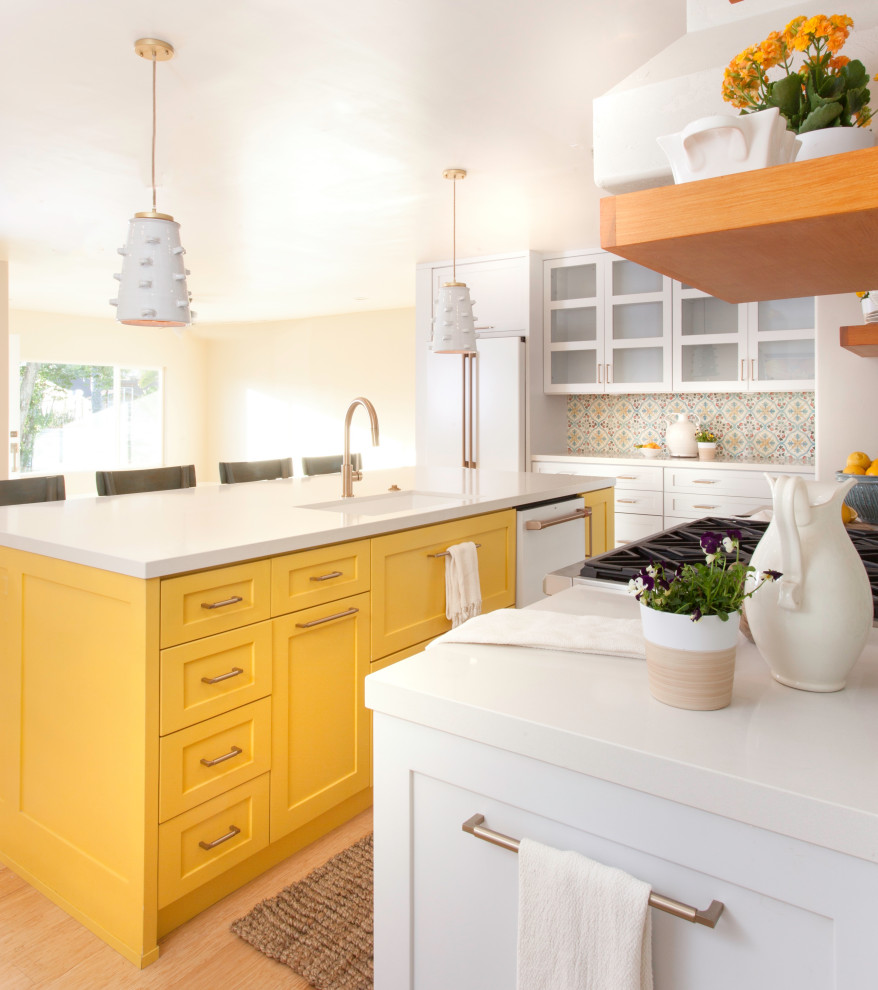 Large country l-shaped eat-in kitchen in San Diego with an undermount sink, shaker cabinets, yellow cabinets, quartz benchtops, white splashback, terra-cotta splashback, coloured appliances, bamboo floors, with island, white benchtop and brown floor.