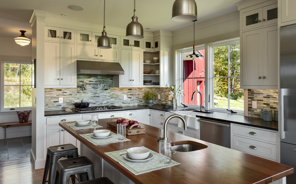 This is an example of a mid-sized traditional l-shaped eat-in kitchen in Portland Maine with a single-bowl sink, shaker cabinets, white cabinets, multi-coloured splashback, glass tile splashback, stainless steel appliances, medium hardwood floors and with island.