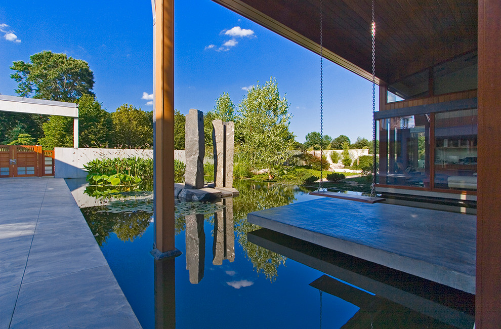 Inspiration for a large contemporary courtyard custom-shaped natural pool in Baltimore with concrete pavers.