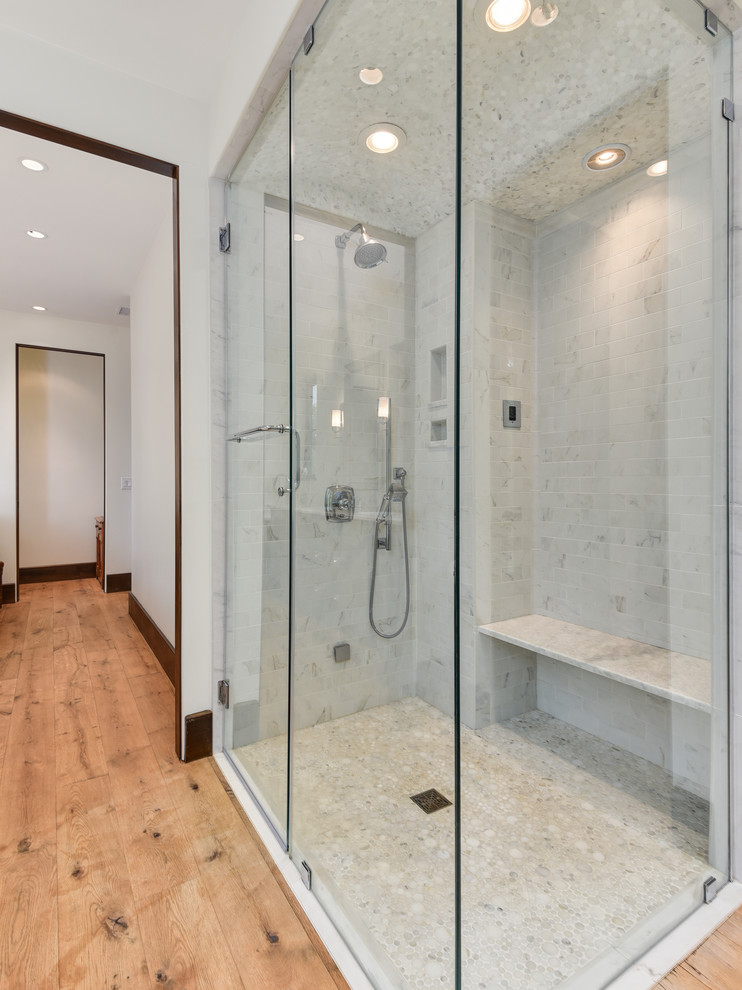 Photo of a mid-sized transitional master bathroom in Other with furniture-like cabinets, dark wood cabinets, a freestanding tub, a corner shower, white tile, marble, white walls, medium hardwood floors, an undermount sink, quartzite benchtops, brown floor and a hinged shower door.