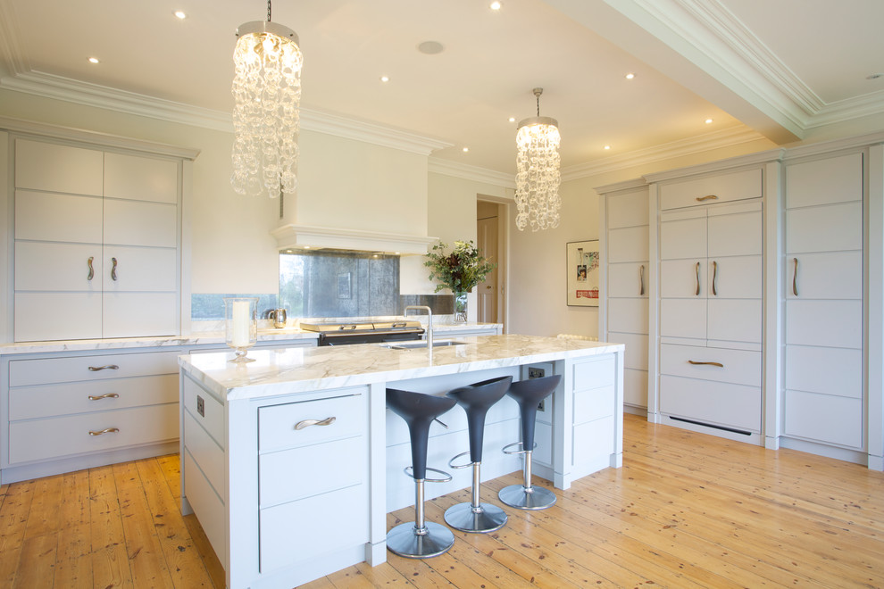 This is an example of a large transitional eat-in kitchen in Wiltshire with flat-panel cabinets, grey cabinets, marble benchtops, mirror splashback, panelled appliances and with island.