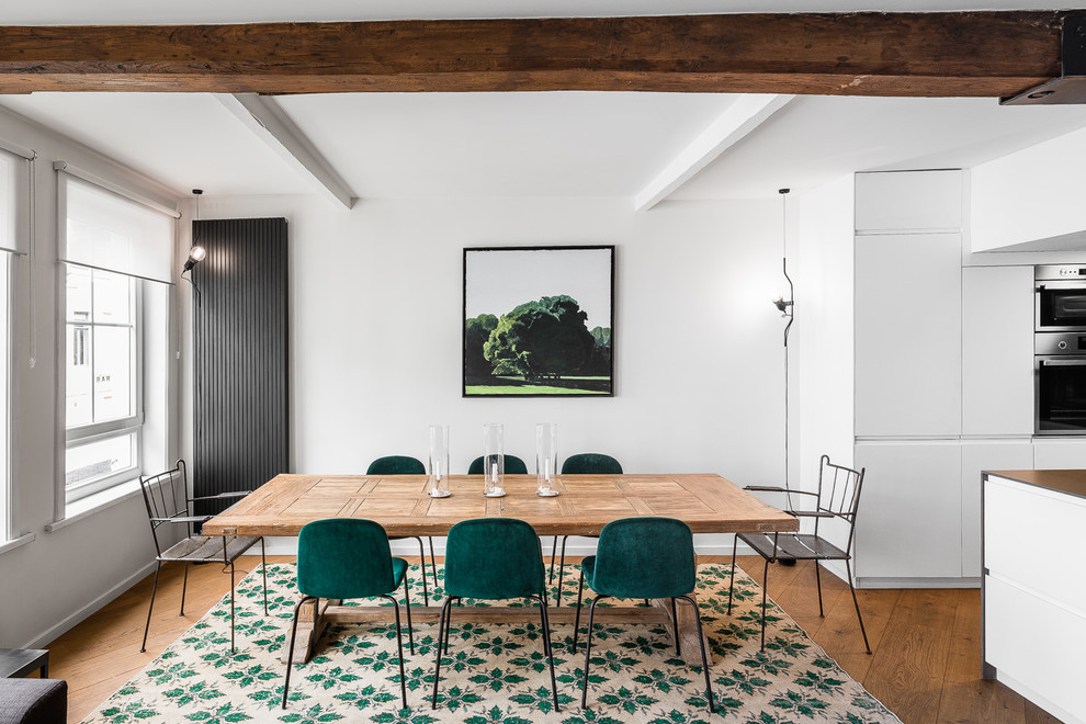 Industrial dining room in Lille with white walls, dark hardwood floors and brown floor.