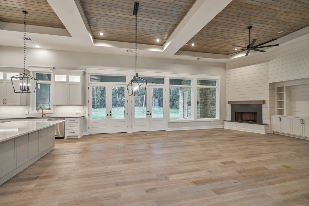 Design ideas for a large traditional open plan games room in Houston with white walls, medium hardwood flooring, a corner fireplace, a timber clad chimney breast, a built-in media unit, brown floors, a wood ceiling and tongue and groove walls.