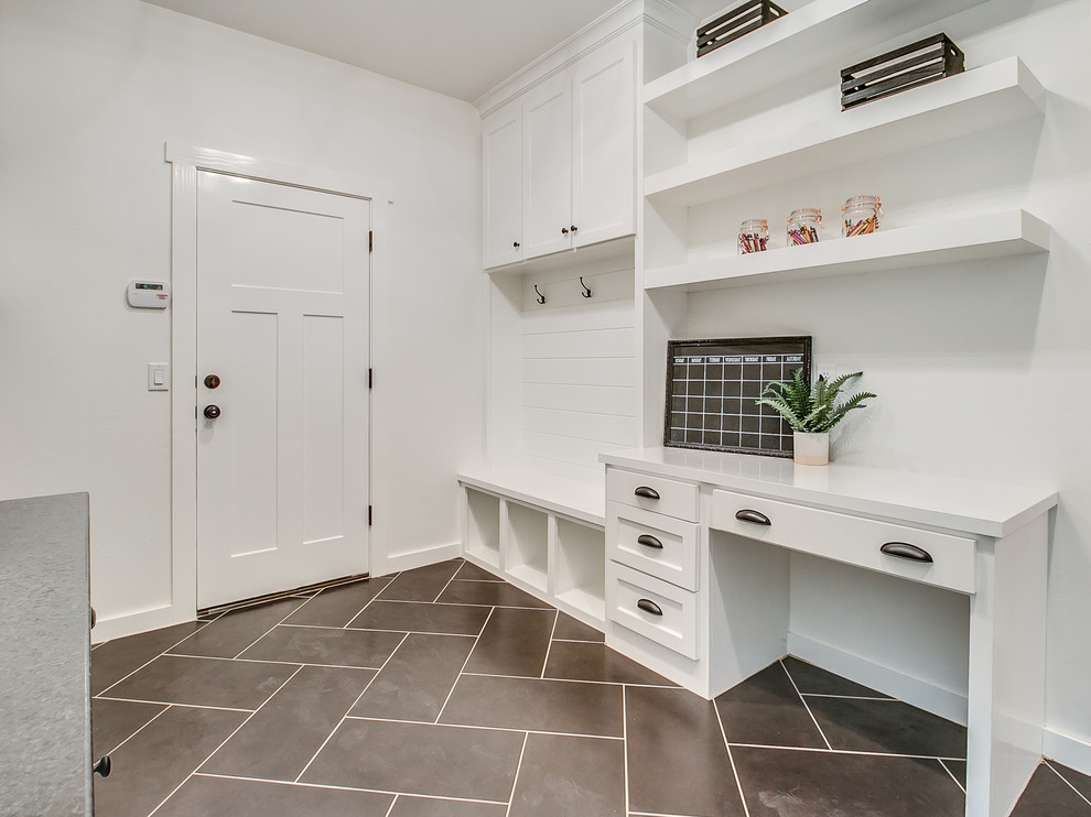 Design ideas for a large country single-wall utility room in Oklahoma City with a drop-in sink, shaker cabinets, white cabinets, quartz benchtops, white walls, ceramic floors, a side-by-side washer and dryer and black floor.