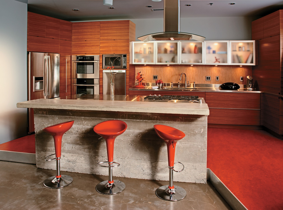 Photo of an industrial kitchen in New York with flat-panel cabinets, medium wood cabinets, brown splashback, stainless steel appliances and stainless steel benchtops.