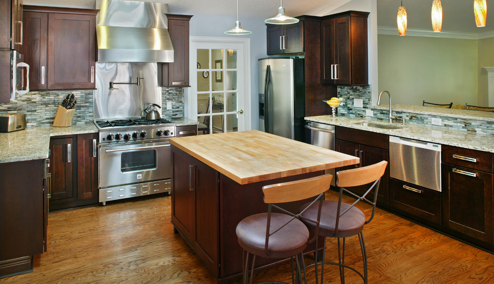 Eat-in kitchen - mid-sized transitional u-shaped light wood floor eat-in kitchen idea in Jacksonville with a single-bowl sink, shaker cabinets, dark wood cabinets, wood countertops, blue backsplash, glass tile backsplash, stainless steel appliances and an island